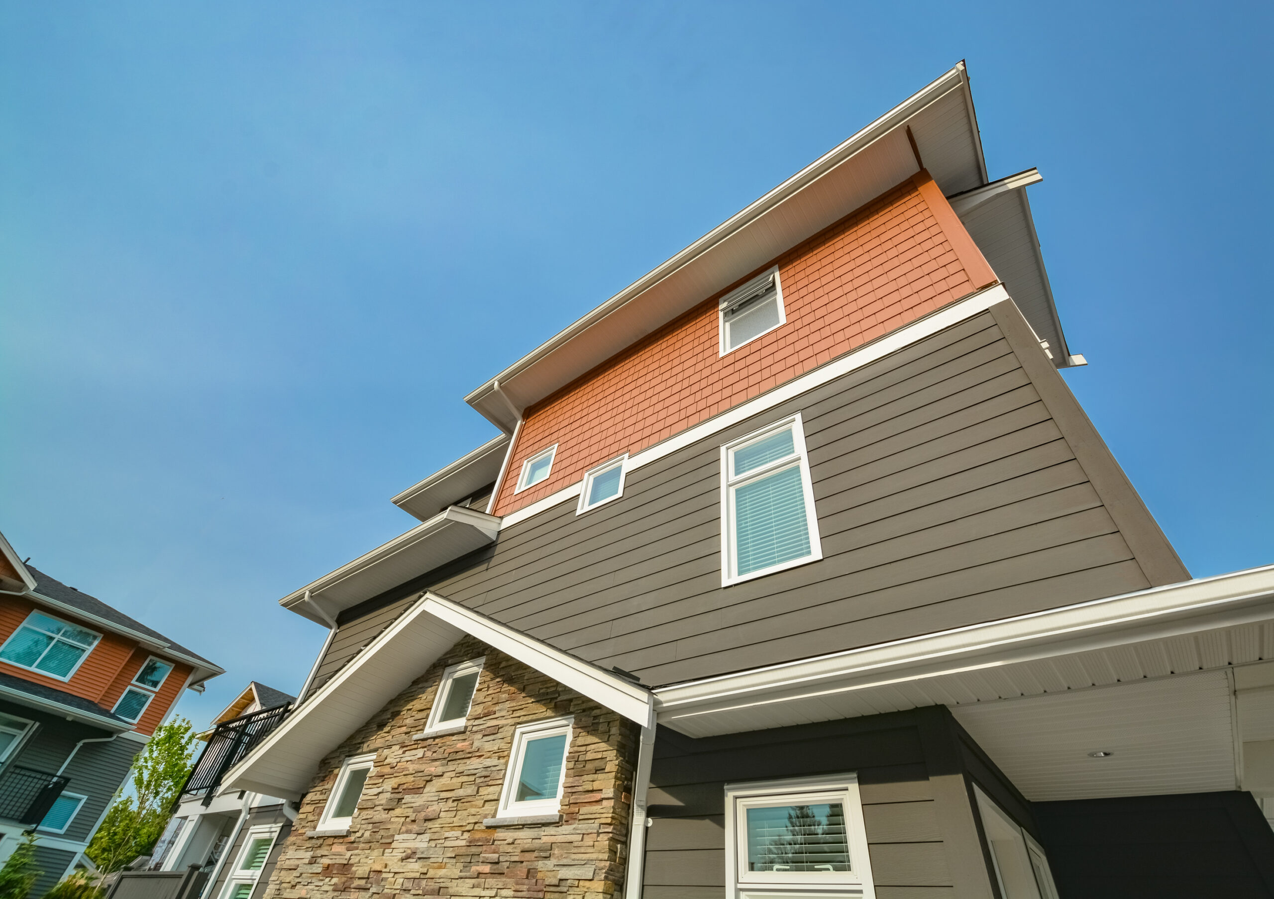 Side wall of brand new residential triplex townhouse on blue sky background. Family house for sale