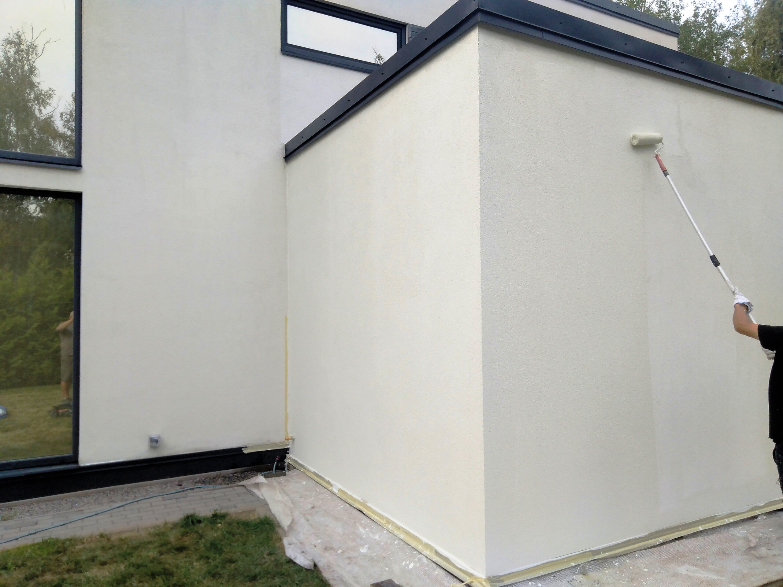 Young man clean the walls by painting white over the old cement wall.